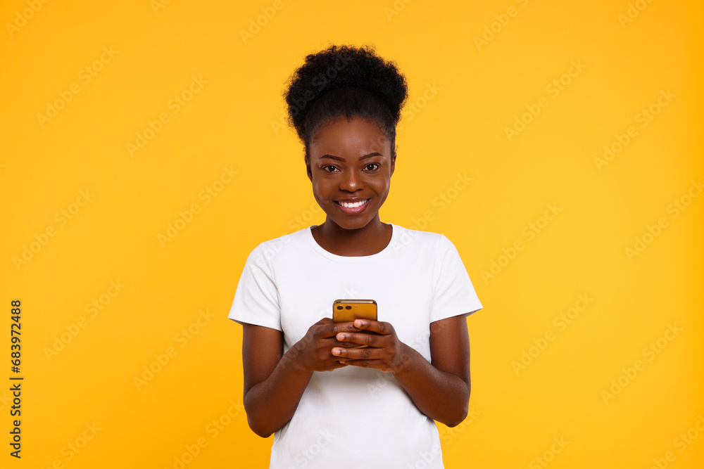 Happy young woman with smartphone on orange background Happy young woman with smartphone on orange background