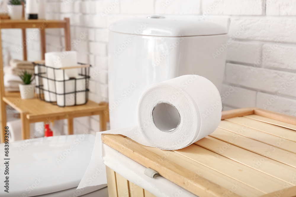 Toilet paper roll on laundry basket in restroom, closeup Toilet paper roll on laundry basket in restroom, closeup