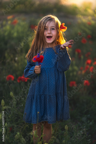 Obraz na płótnie little girl in blue dress on sunset ni poppy seed red flowers green grass summer field bloom cute alone w salonie