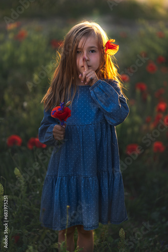 Obraz na płótnie little girl in blue dress on sunset ni poppy seed red flowers green grass summer field bloom cute alone w salonie
