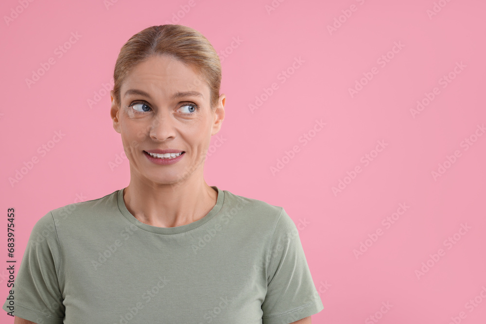 Embarrassed woman on pink background. Space for text Embarrassed woman on pink background. Space for text