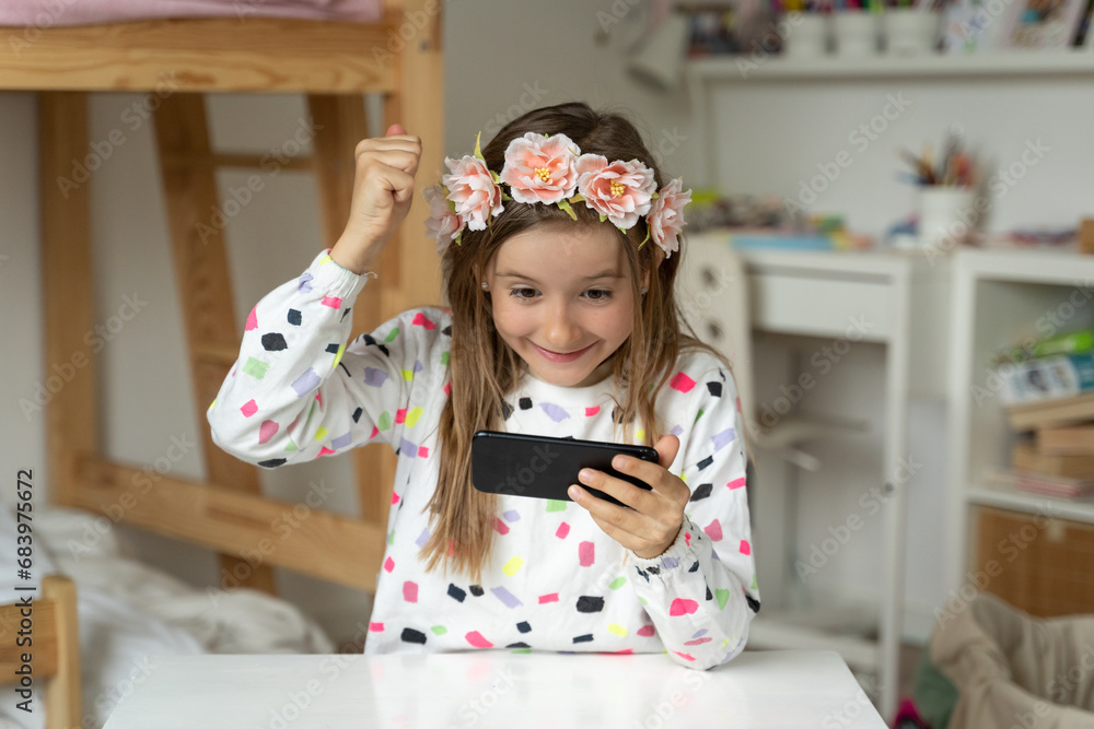 happy little girl in her play room smart phone addicted watching video video game expressions screaming