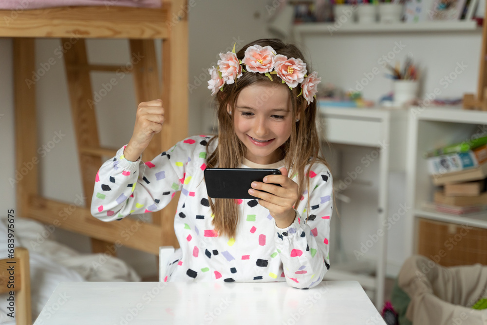 happy little girl in her play room smart phone addicted watching video video game expressions screaming