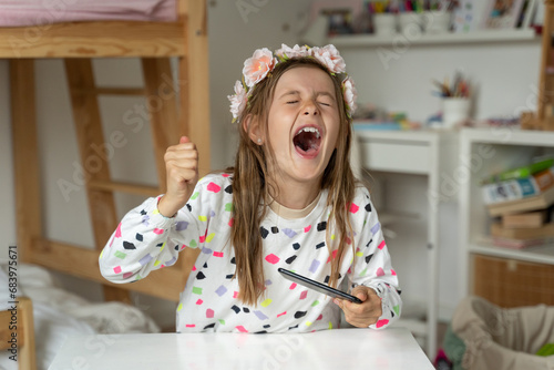 Obraz na płótnie happy little girl in her play room smart phone addicted watching video video game expressions screaming w salonie