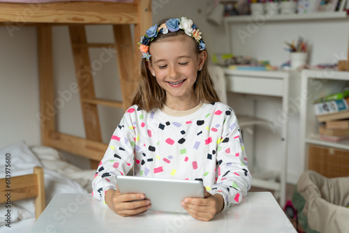 Obraz na płótnie happy little girl in her play room watching play learn tablet mobile electronic book happy game w salonie