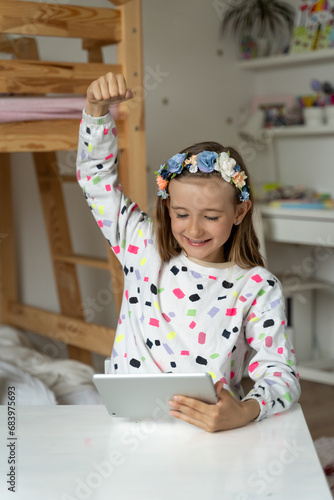 Obraz na płótnie happy little girl in her play room watching play learn tablet mobile electronic book happy game w salonie