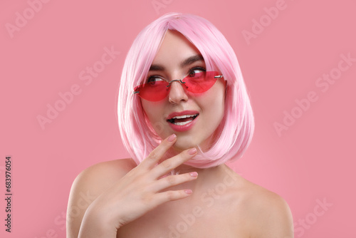 Pink look. Beautiful girl in wig and bright sunglasses on color background
