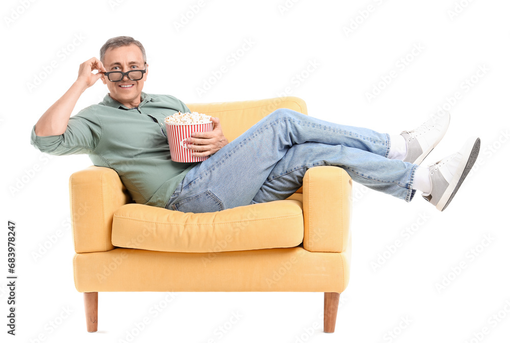Mature man with 3D glasses and popcorn watching movie in armchair on white background