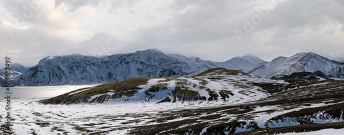 Season change in the Icelandic highlands.  Colorful Landmannalaugar mountains under snow cover in autumn. Frostastadavatn lake at the foot of the mountains. photo