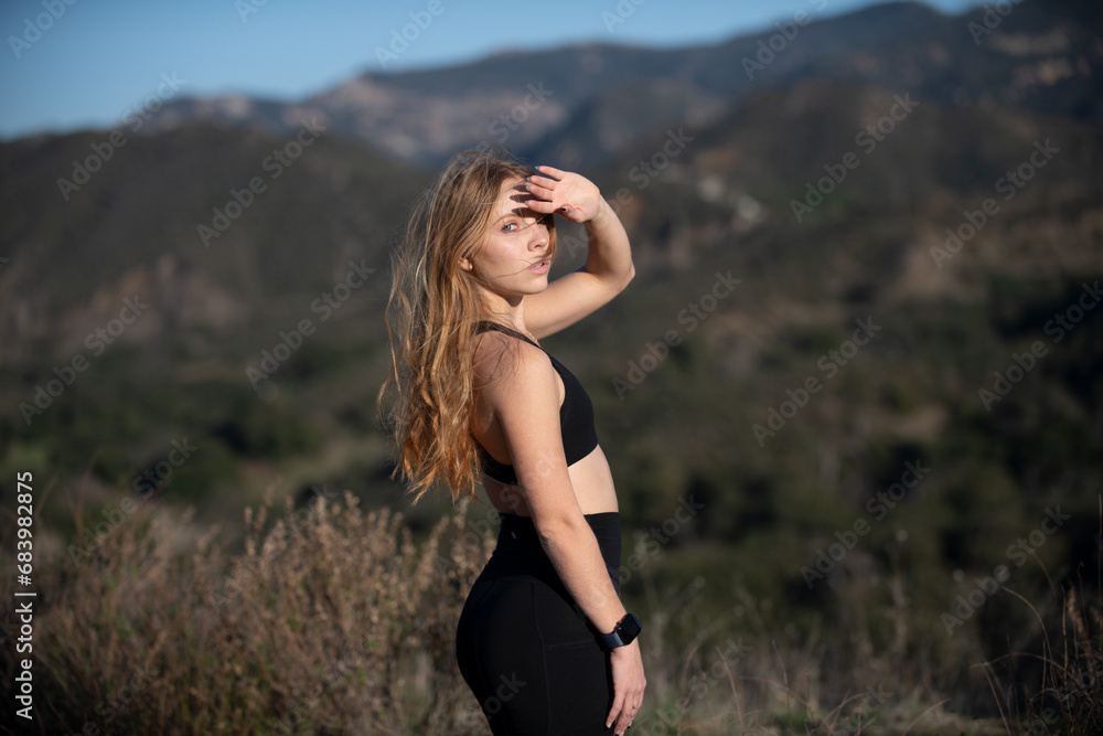 Woman hiking. Girl on mountain peak looking at mountain valley at sunset in summer. Landscape with sporty young woman, foggy hills, forest, sky. Travel and tourism. Hiking.
