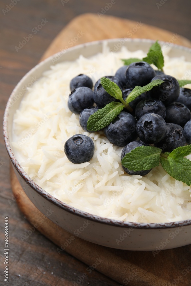Bowl of delicious rice porridge with blueberries and mint on table, closeup Bowl of delicious rice porridge with blueberries and mint on table, closeup