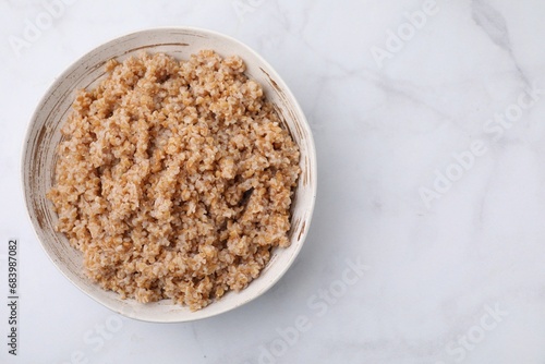 Foto Tasty wheat porridge in bowl on white marble table, top view