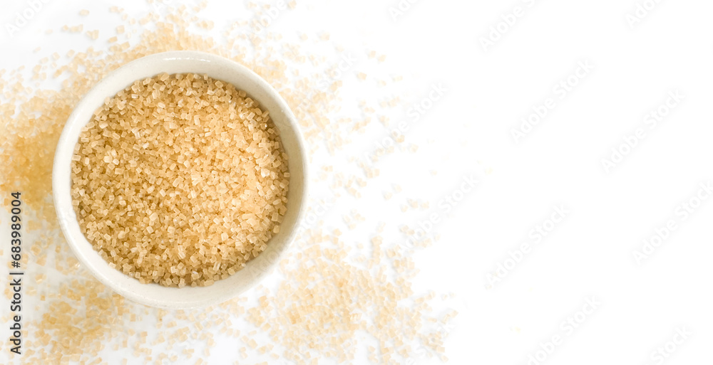 Small bowl of raw brown sugar with scattered crystals on white background Small bowl of raw brown sugar with scattered crystals on white background