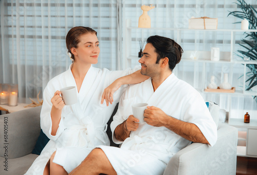 Beauty or body treatment spa salon vacation lifestyle concept with couple wearing bathrobe relaxing with drinks in luxurious hotel spa or resort room. Vacation and leisure relaxation. Quiescent