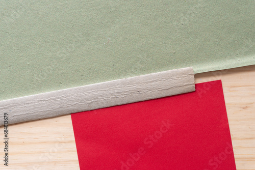 paper background composed of bookbinding spine stiffener or stripe, rough green scrapbooking paper sheet, and blank red card photo