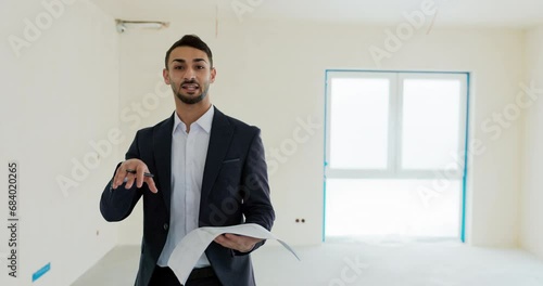 Happy successful middle eatern real estate agent holding building plan in hands talking about a new modern building house in a countryside. Delighted male showing house for sale after renovation. photo