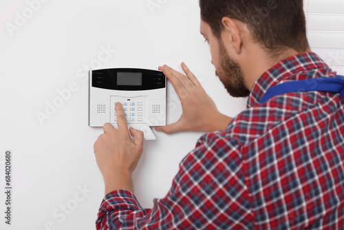 Man entering code on security alarm system at home