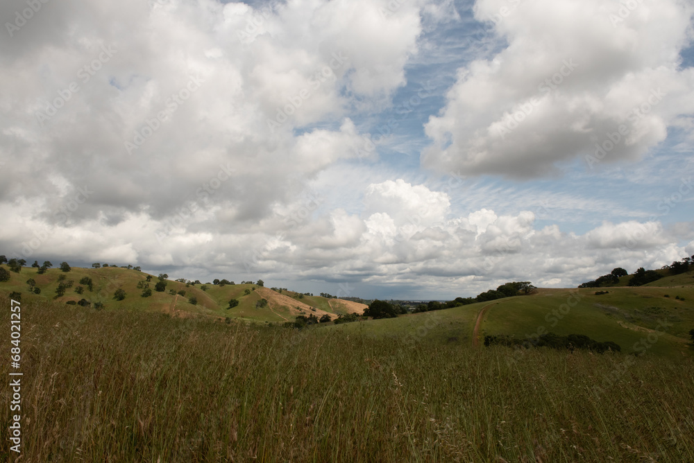 Fototapeta premium The Lagoon Valley Park in Vacaville, California, USA, offers a sweeping view of the rolling mountains of the city, on a partly cloudy day with sky copy space