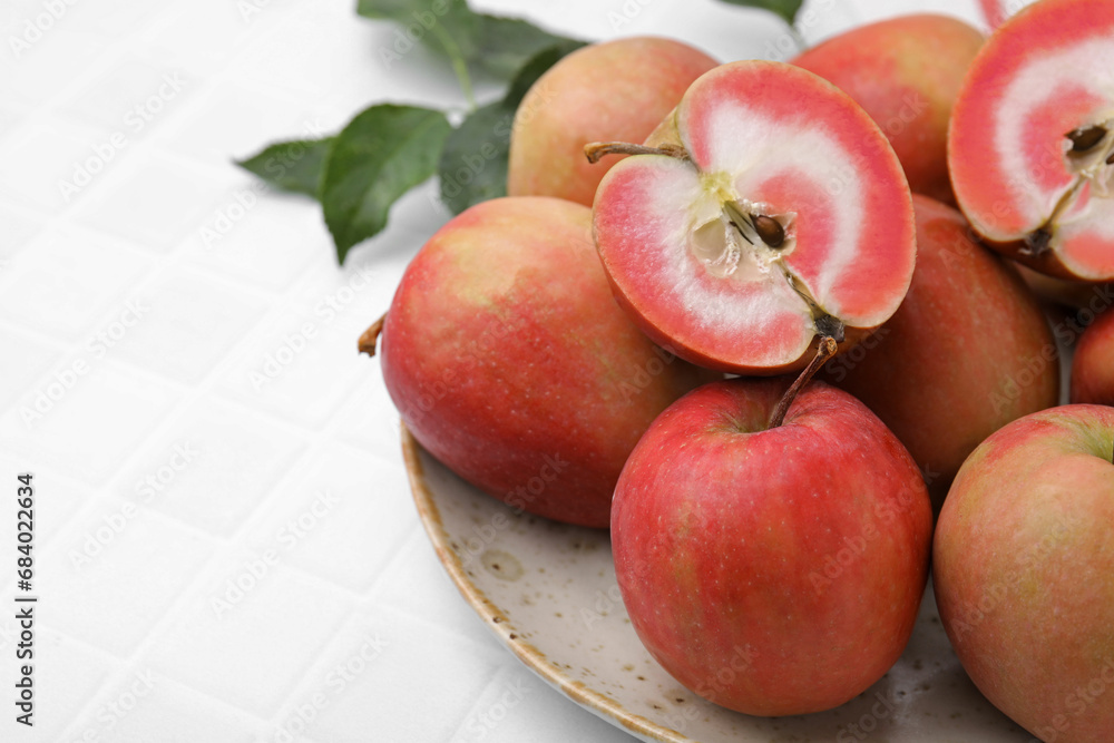 Tasty apples with red pulp and leaves on white tiled table, closeup. Space for text Tasty apples with red pulp and leaves on white tiled table, closeup. Space for text