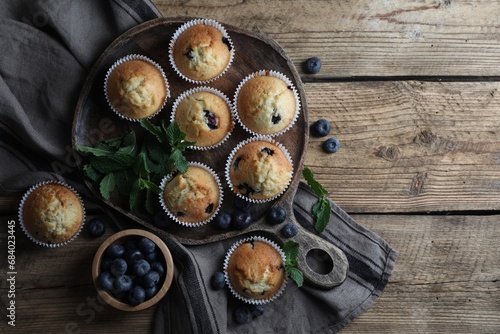 Delicious sweet muffins with blueberries and mint on wooden table, flat lay. Space for text