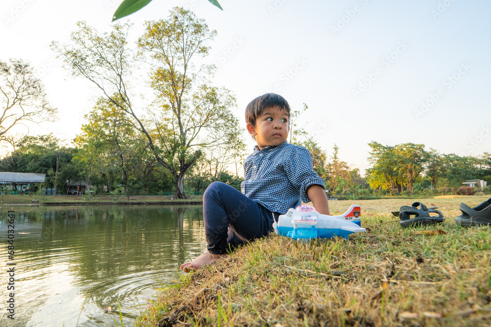 Toddler asian boy playing in city park river side outdoor recreation