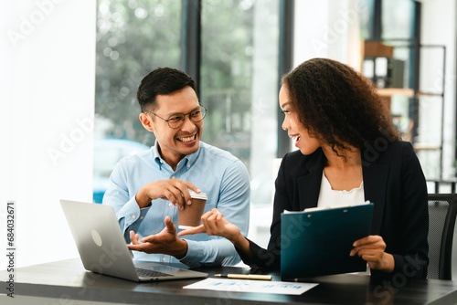 Asian business man and African American woman engaging in business discussion, possibly about merger or joint venture. two companies become one, one of companies often survives while other disappears