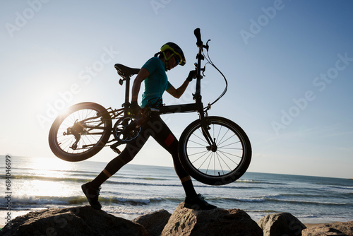 Woman taking a folding bike on sunrise seaside road
