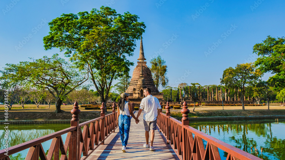Some men and women visit Wat Sa Sit, Sukhothai Old City, Thailand. Ancient city and culture of South Asia Thailand, A couple visit Sukhothai Historical Park - obrazy, fototapety, plakaty 