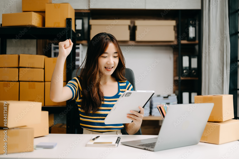 Startup small business SME, Entrepreneur owner woman using smartphone or tablet taking receive and checking online purchase shopping order Startup small business SME, Entrepreneur owner woman using smartphone or tablet taking receive and checking online purchase shopping order