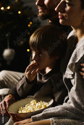 Happy family  celebrate Christmas  watch movies and eat popcorn and pizza near the New Year tree. Vertical photo
