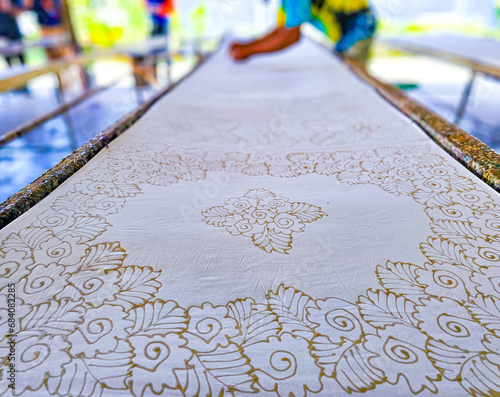 Making batik by drawing beautiful patterns by hand.