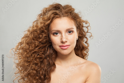 Glamorous young fashion model woman with natural makeup, clear skin and curly hairstyleposing on white background
