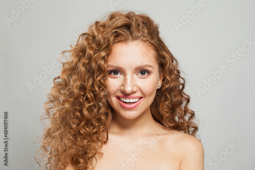 Laughing young fashion model woman with natural makeup, clear skin and curly hairstyleposing on white background