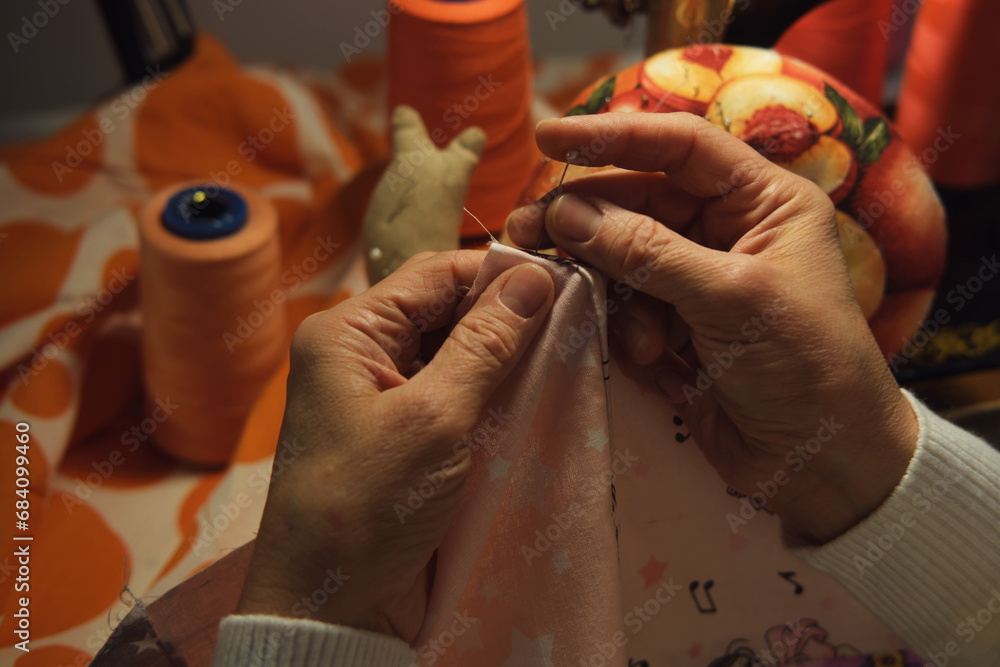Close-up of a woman's hands sewing on a fabric. Close-up of a woman's hands sewing on a fabric.