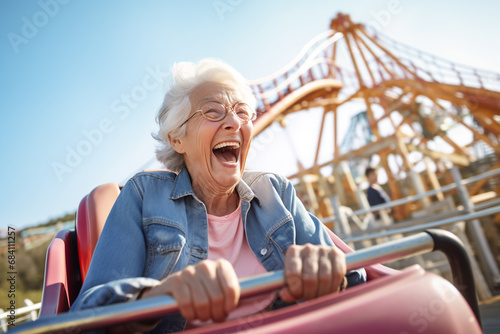 Happy Senior woman with gray hair riding a rollercoaster at amusement park and scream photo