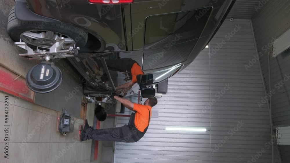 A car mechanic makes a camber in a car. Car chassis repair. Car service. Vertical video A car mechanic makes a camber in a car. Car chassis repair. Car service. Vertical video