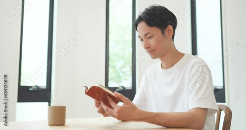 自宅のリビングで読書をする若い男性