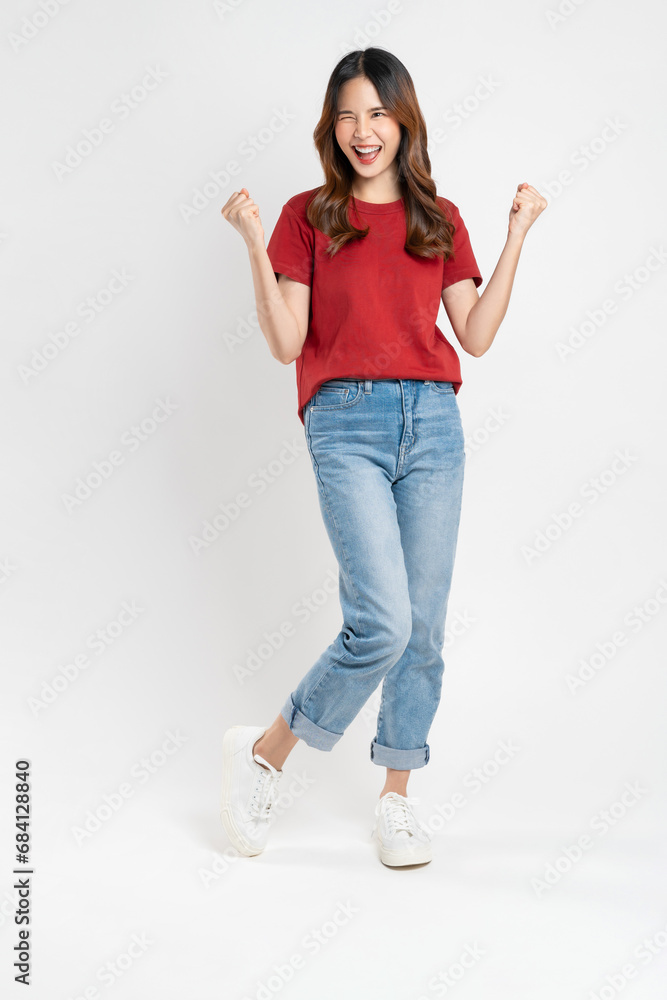 Happy smiling young woman wearing red t-shirt with raises arms and fists clenched with shows strong powerful, celebrating victory expressing success. Happy smiling young woman wearing red t-shirt with raises arms and fists clenched with shows strong powerful, celebrating victory expressing success.