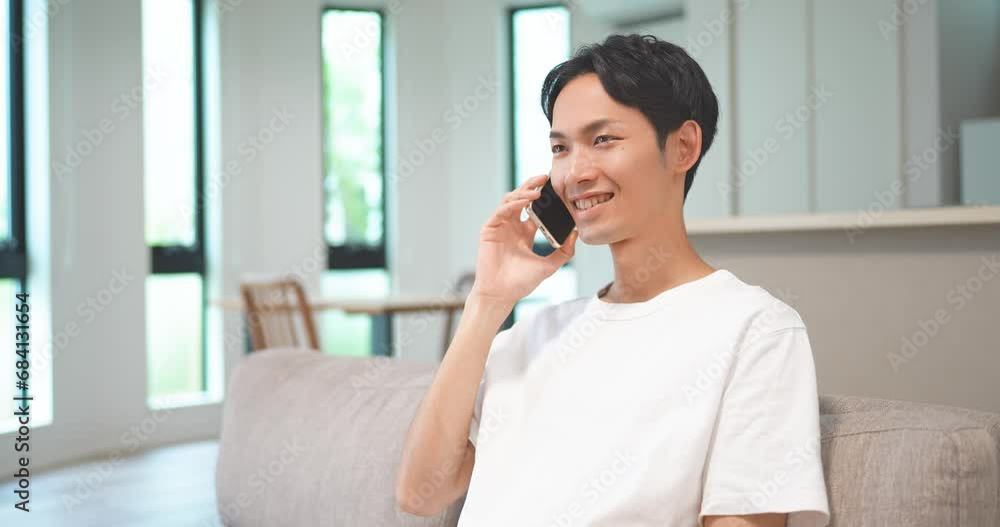 ソファに座ってスマートフォンで電話をする男性 ソファに座ってスマートフォンで電話をする男性