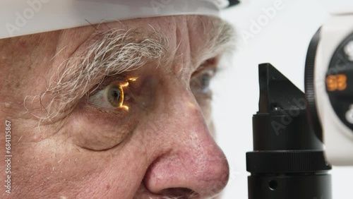 Close-up of a senior man having his vision tested on an ophthalmology diagnostic vision testing equipment. Old man doing eye test with non contact tonometer, checking vision at optical clinic photo