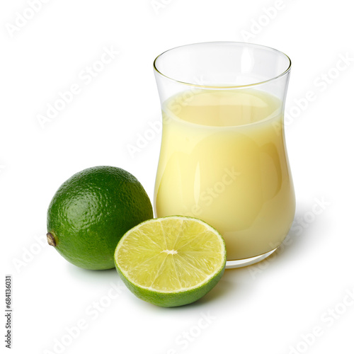 Glass with lime juice and green lime in front isolated on white background © Picture Partners