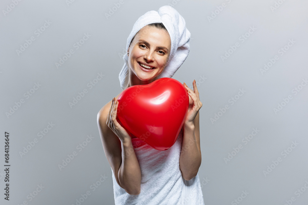 Beautiful and joyful woman wearing white towels and holding a red heart. Valentine's Day Beautiful and joyful woman wearing white towels and holding a red heart. Valentine's Day