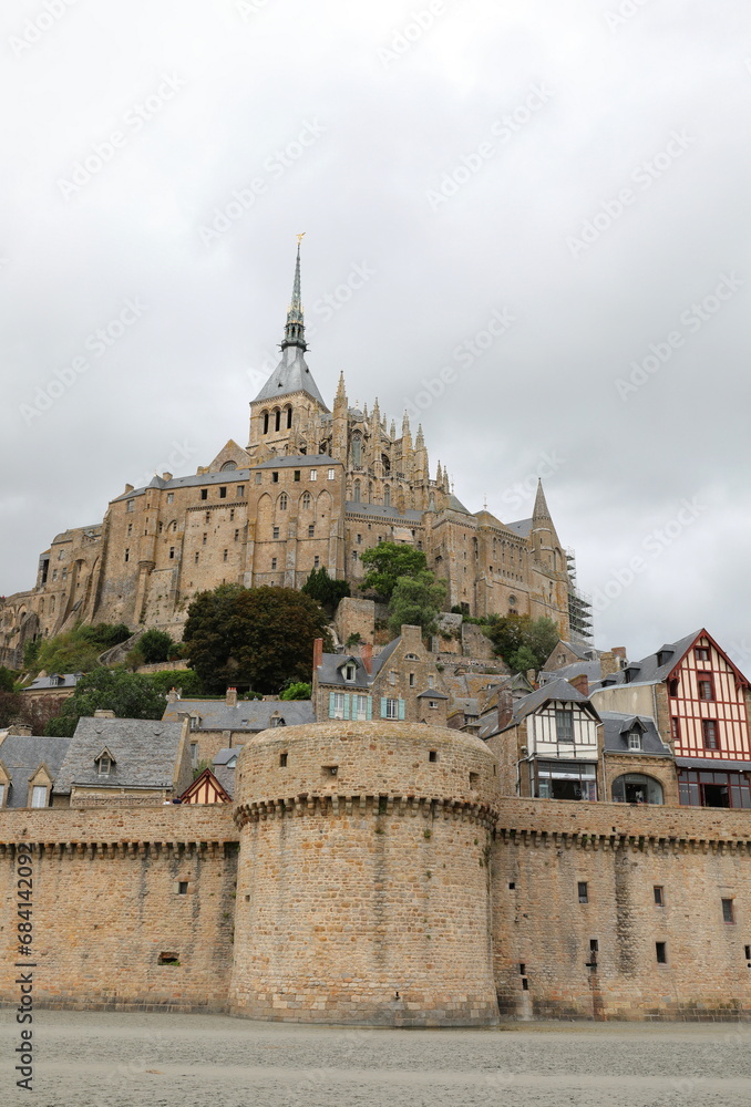 ancient Mont Saint Michel abbey and the village walls of the hill during low tide with the beach