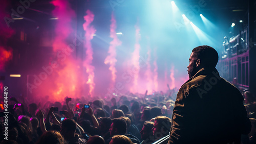 A lone Dark-skinned man in the audience at a concert looks out at the audience.