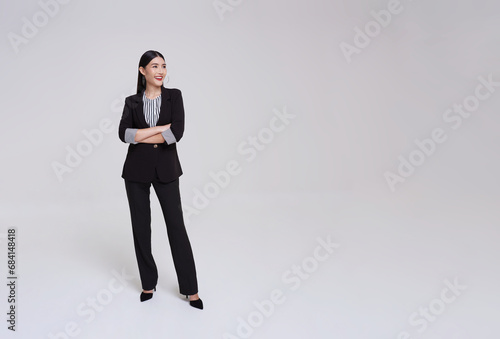 Young asian business woman in suit with arms crossed and smile standing pose on isolated white copy space background.