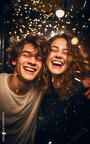 Two young teenagers, boy and girl, are laughing and joyful at a New Year's Eve party