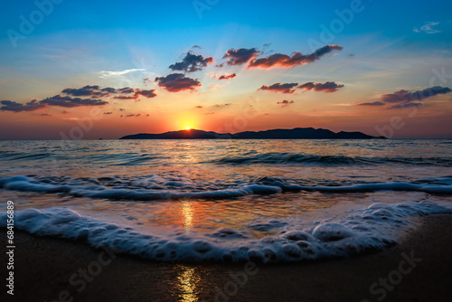 Picture of the beach at sunset with the foreground being a sandy beach and sea water. The background is Khram Yai Island. The name of the beach is Haad So, Chonburi Province, Sattahip District. photo