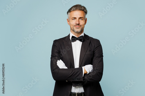 Adult confident barista male waiter butler man wear shirt black suit bow tie elegant uniform work at cafe hold hands crossed folded isolated on plain light blue background Restaurant employee concept photo