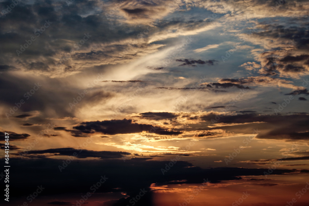 The sun setting behind dark clouds in the sky.