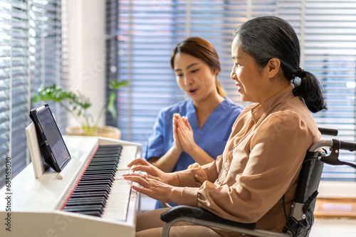 Portrait of asian nurse physiotherapist carer helping smiling and having fun teaching and play piano music lesson with asian senior elderly woman at home visit.senior retirement care concept